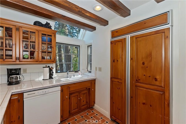 kitchen with beamed ceiling, dishwasher, sink, and tile counters