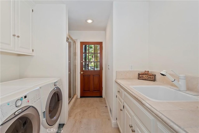 washroom with sink, light hardwood / wood-style flooring, cabinets, and independent washer and dryer