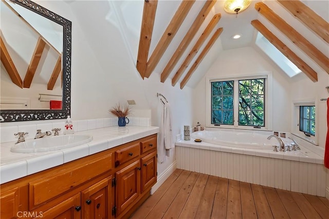 bathroom with wood-type flooring, vaulted ceiling with beams, vanity, and a tub to relax in