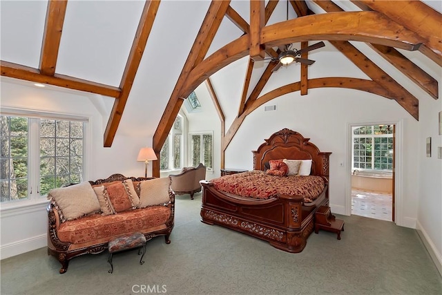 carpeted bedroom featuring multiple windows, vaulted ceiling with beams, and connected bathroom