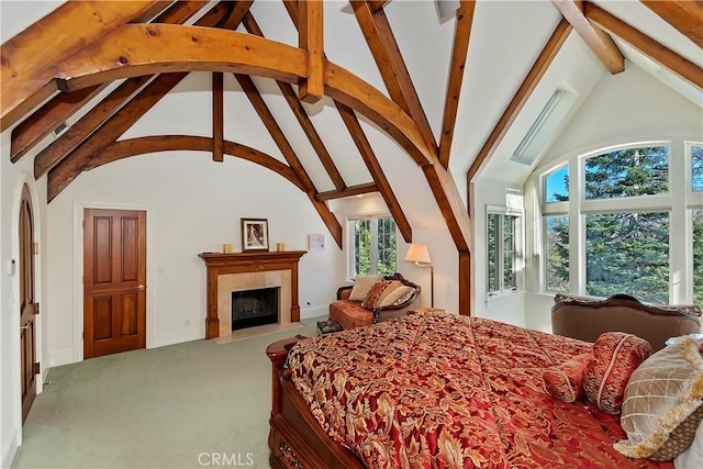 carpeted bedroom featuring beamed ceiling, a fireplace, and high vaulted ceiling