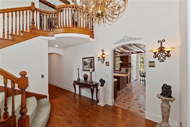 foyer entrance featuring an inviting chandelier, a towering ceiling, and dark hardwood / wood-style floors