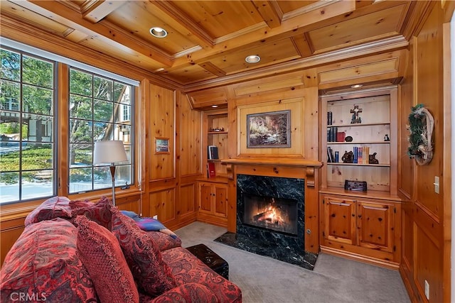 carpeted living room featuring coffered ceiling, wood walls, wooden ceiling, built in features, and a premium fireplace