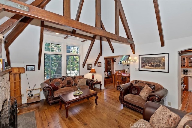 living room featuring beamed ceiling, wood-type flooring, a stone fireplace, and high vaulted ceiling