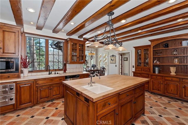 kitchen featuring appliances with stainless steel finishes, a kitchen island with sink, sink, and butcher block countertops