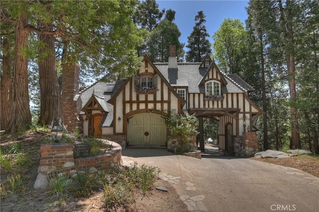 29223 Pigeon Hawk Ln, Lake Arrowhead, CA 92352 - english style home featuring a chimney, stucco siding, roof with shingles, and driveway