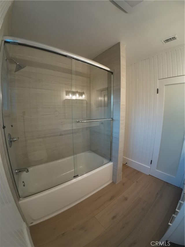 bathroom featuring hardwood / wood-style flooring and enclosed tub / shower combo