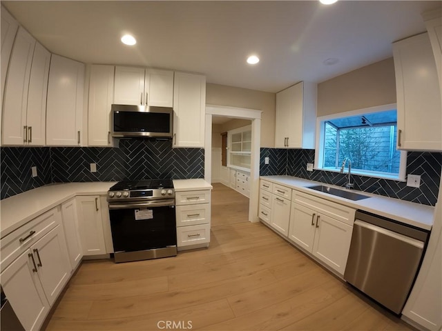 kitchen featuring light wood-type flooring, appliances with stainless steel finishes, sink, and white cabinets