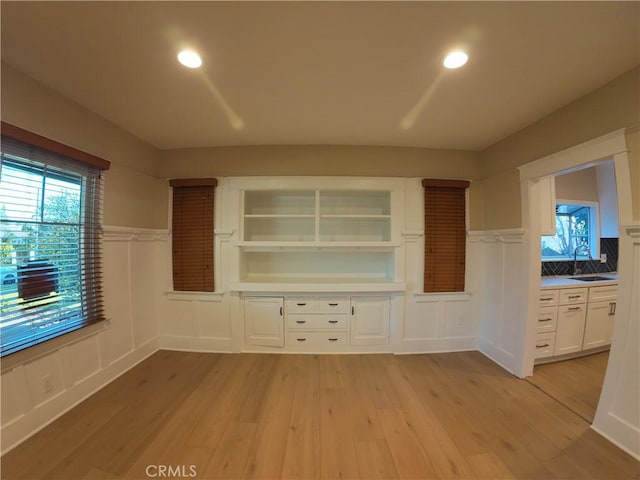 unfurnished living room with sink, light hardwood / wood-style flooring, and a wealth of natural light