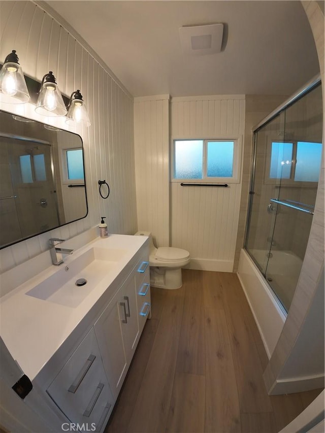 full bathroom with wood-type flooring, toilet, combined bath / shower with glass door, and vanity