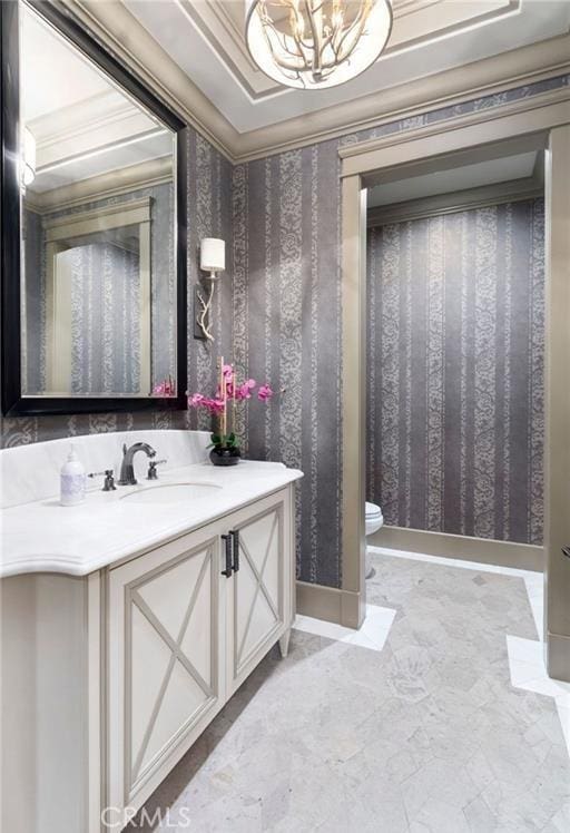 bathroom featuring a notable chandelier, wallpapered walls, vanity, and crown molding