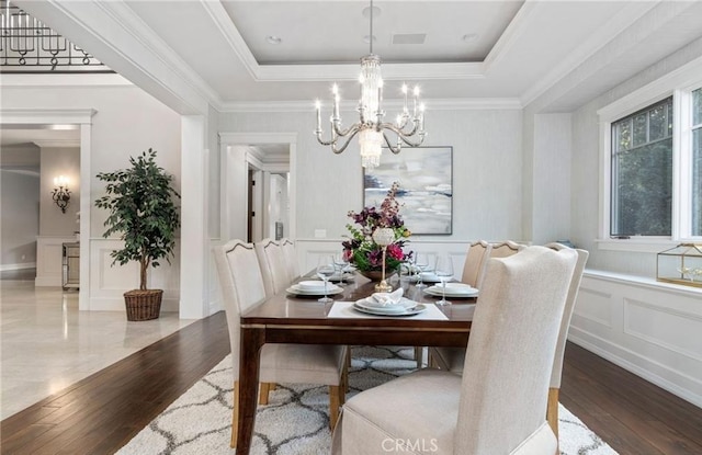 dining room with a tray ceiling, wood finished floors, and a decorative wall