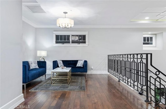 living room with dark wood-style floors, baseboards, crown molding, and an inviting chandelier