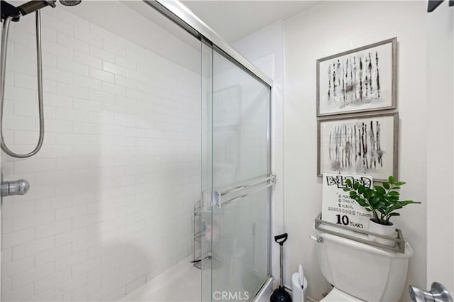 bathroom featuring a shower with door and toilet