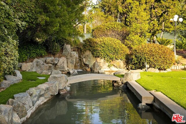 view of property's community featuring a small pond and a yard