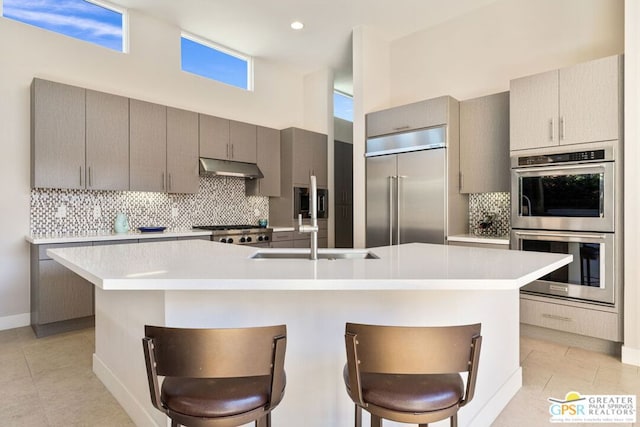 kitchen with appliances with stainless steel finishes, a kitchen island with sink, and a breakfast bar area