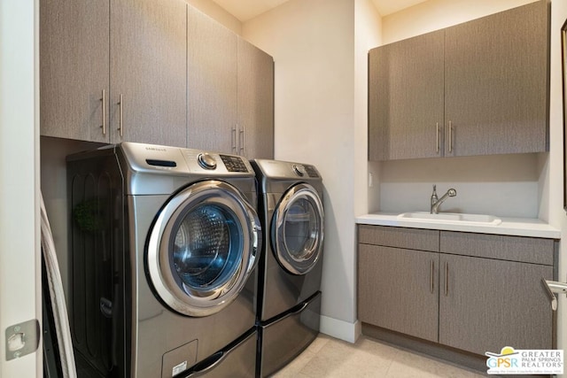 laundry area featuring cabinets, sink, light tile patterned floors, and washing machine and clothes dryer