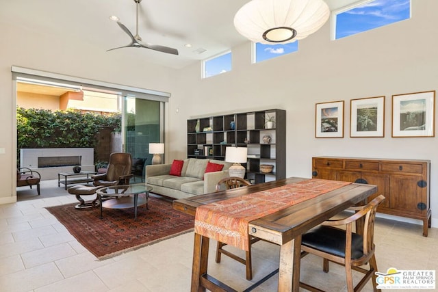 tiled dining space featuring a towering ceiling and ceiling fan