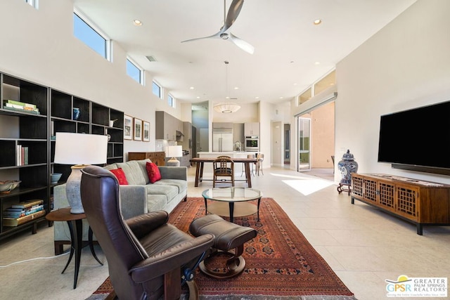 tiled living room featuring ceiling fan and a high ceiling