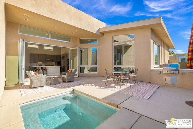 rear view of house featuring outdoor lounge area, exterior kitchen, and a patio