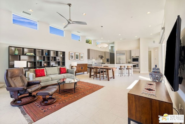 living room with plenty of natural light, light tile patterned flooring, ceiling fan, and a high ceiling