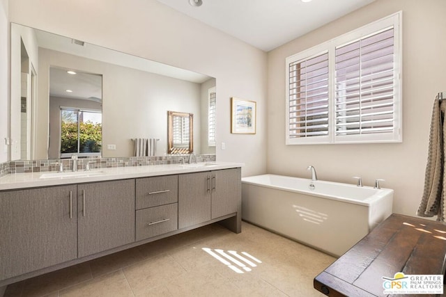 bathroom with tile patterned flooring, a bathing tub, and vanity