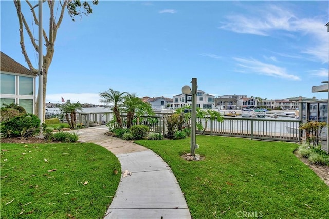 surrounding community with a water view and a yard