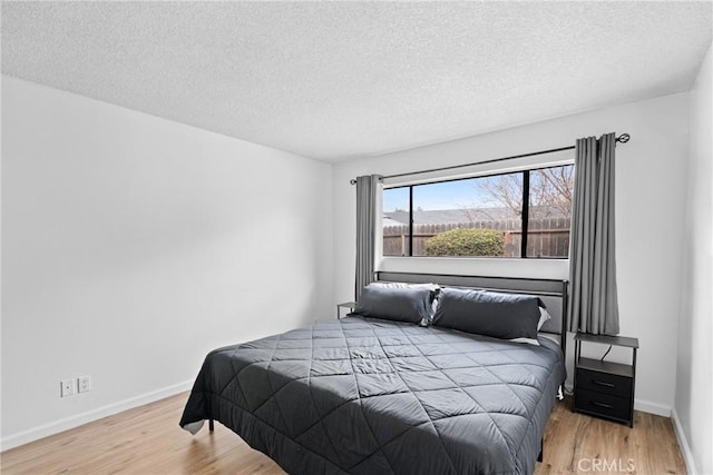 bedroom with light hardwood / wood-style floors and a textured ceiling