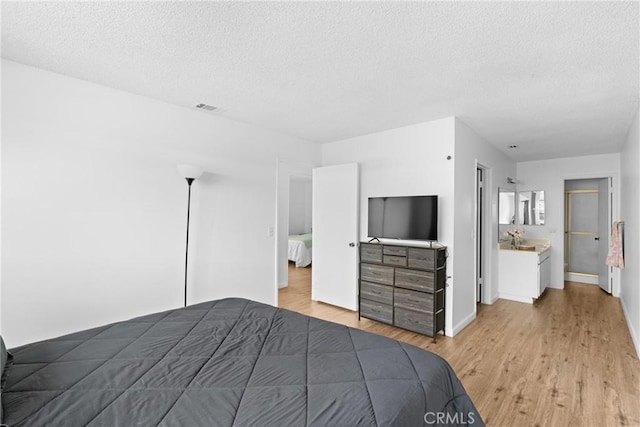 unfurnished bedroom featuring sink, a textured ceiling, and light hardwood / wood-style flooring