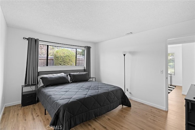 bedroom featuring light hardwood / wood-style flooring and a textured ceiling