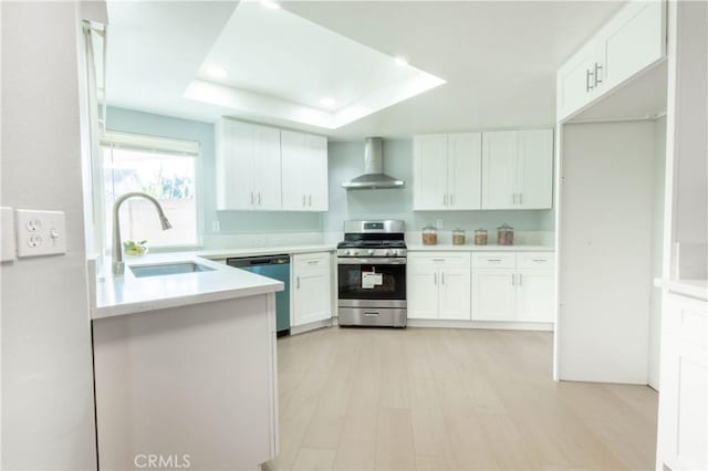 kitchen featuring white cabinetry, sink, stainless steel appliances, light wood-type flooring, and wall chimney exhaust hood