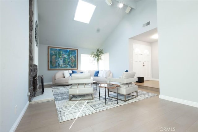 living room featuring hardwood / wood-style flooring, a skylight, high vaulted ceiling, and beamed ceiling