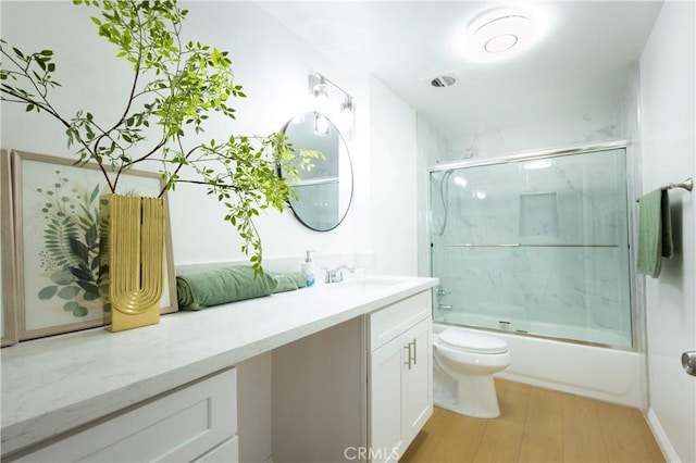 full bathroom featuring vanity, hardwood / wood-style flooring, toilet, and combined bath / shower with glass door