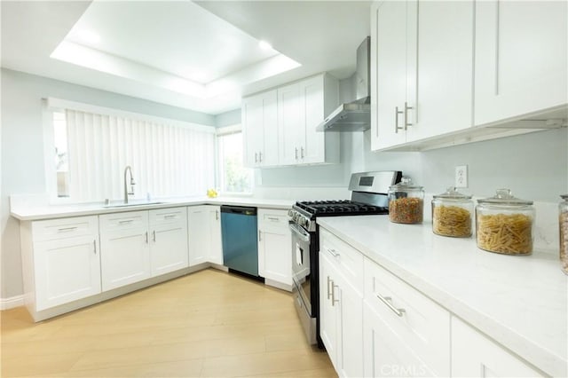 kitchen featuring white cabinets, appliances with stainless steel finishes, sink, and wall chimney range hood