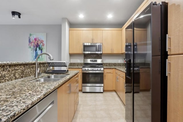 kitchen featuring light stone countertops, appliances with stainless steel finishes, sink, and light brown cabinets