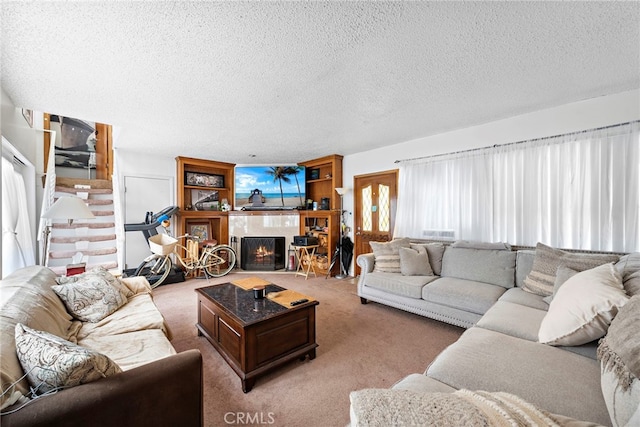 living room with light colored carpet, a tiled fireplace, and a textured ceiling