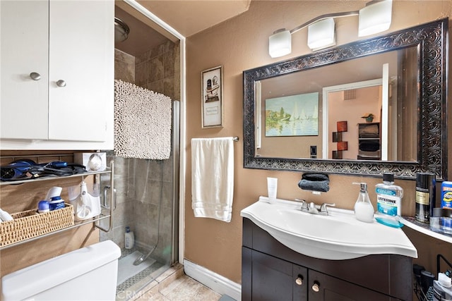 bathroom with a tile shower, vanity, and toilet