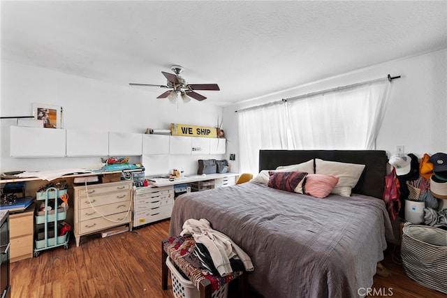 bedroom with ceiling fan, dark wood-type flooring, and a textured ceiling