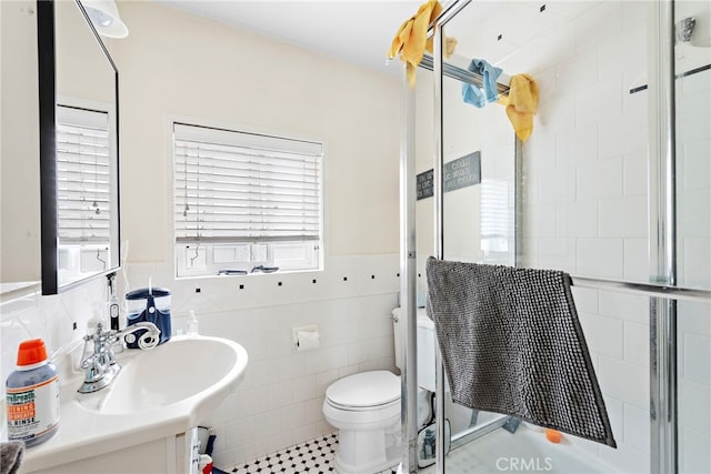 bathroom featuring tile walls, vanity, a shower with shower door, and toilet