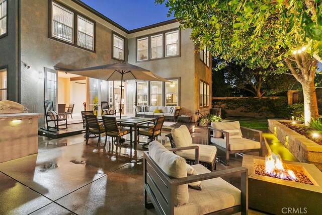 exterior space featuring a patio area, an outdoor living space with a fire pit, and stucco siding