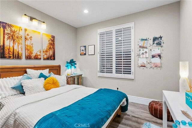 bedroom with baseboards, wood finished floors, and recessed lighting