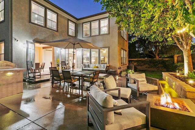 exterior space with stucco siding, a patio area, outdoor dining area, and an outdoor living space with a fire pit