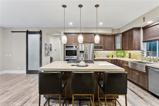 kitchen featuring stainless steel appliances, a center island, light countertops, and a kitchen bar