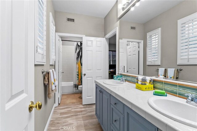 full bathroom featuring toilet, visible vents, a sink, and shower / tub combo with curtain