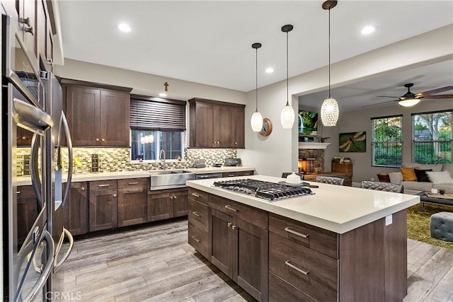 kitchen with pendant lighting, sink, dark brown cabinetry, a kitchen island, and decorative backsplash