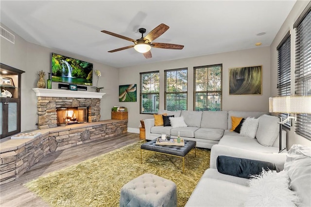 living room featuring ceiling fan, hardwood / wood-style floors, and a fireplace