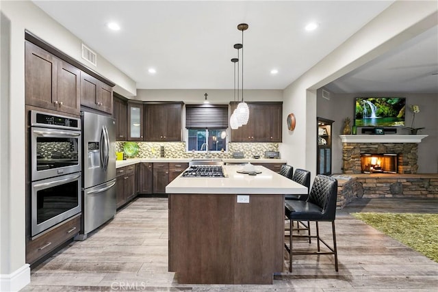 kitchen with a kitchen island, appliances with stainless steel finishes, dark brown cabinets, and a kitchen bar