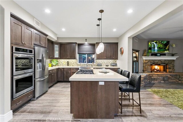 kitchen with dark brown cabinetry, stainless steel appliances, a breakfast bar area, and light countertops