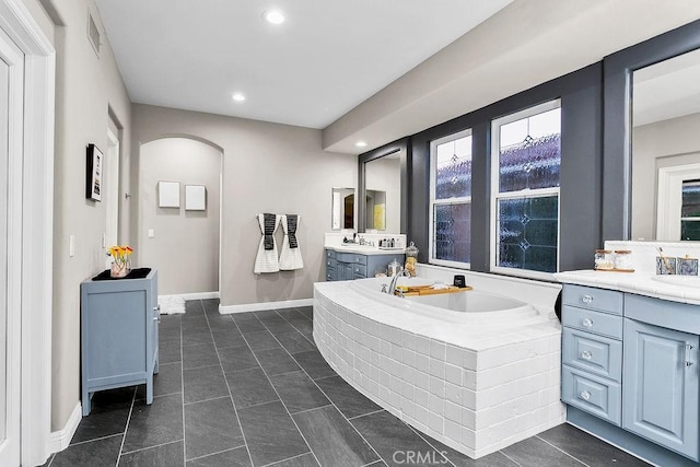 bathroom with a relaxing tiled tub, vanity, tile patterned flooring, and plenty of natural light