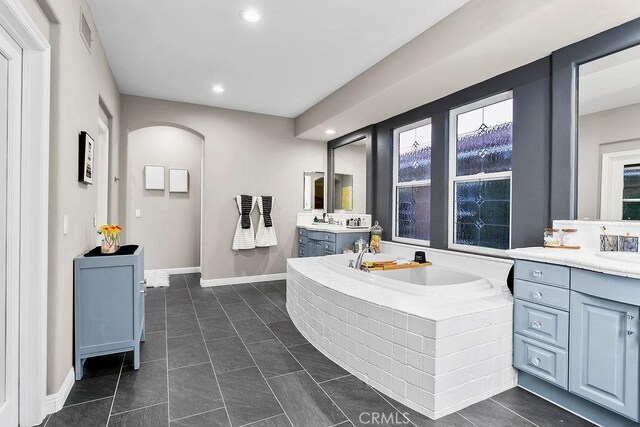 full bathroom with visible vents, two vanities, a garden tub, tile patterned flooring, and a sink